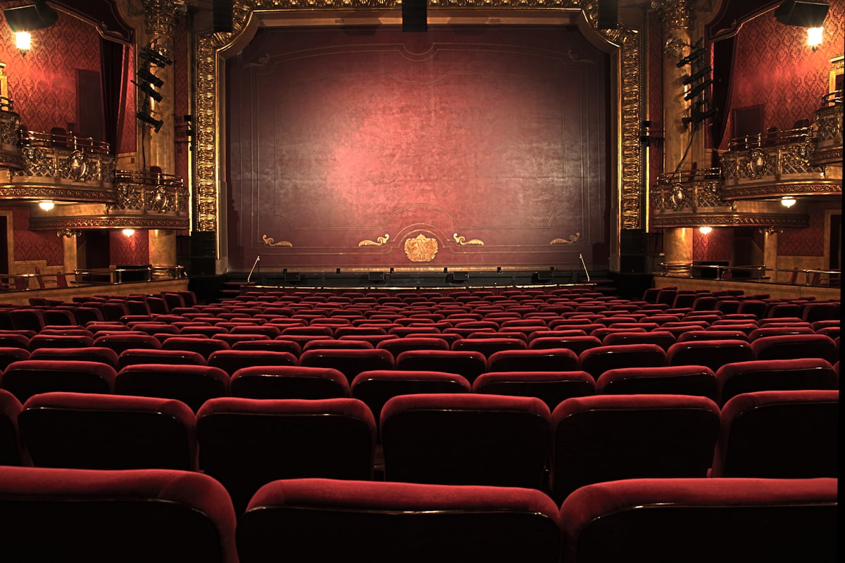 Historischer Theatersaal mit rotem Samtvorhang und goldenen Rängen